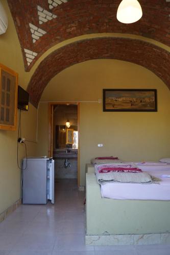 two beds in a room with a brick ceiling at Rahala Safari Hotel in Qasr Al Farafirah