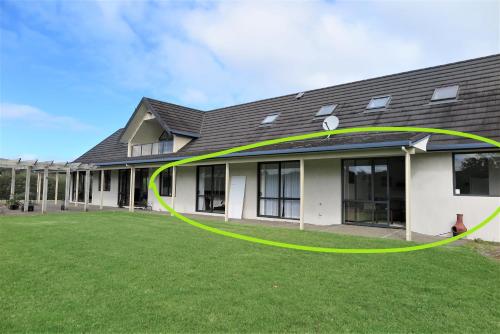 a building with a green circle on the grass at Kaka Lodge at Kotare House in Tawharanui