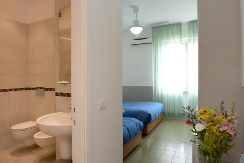 a bathroom with a bed and a toilet and a sink at Hotel Puntabella in Varazze