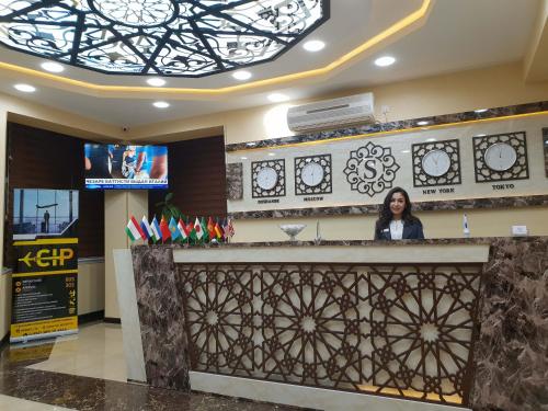 a woman standing at a counter in a lobby at SAFIR BUSINESS HOTEL o in Dushanbe