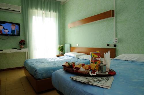 a hotel room with two beds and a tray of food on a table at Hotel Puntabella in Varazze
