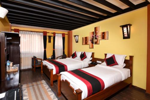 2 camas en una habitación con paredes amarillas en Karma Boutique Hotel en Katmandú