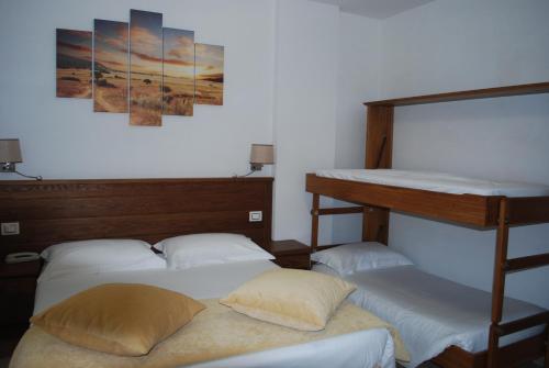 ロッカラーゾにあるHotel Il Bucaneveのベッド3台とポスター付きの部屋