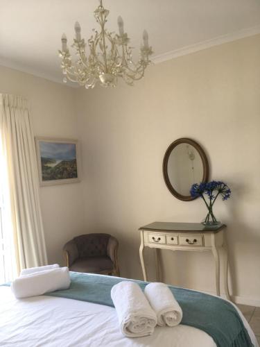 a bedroom with a bed and a mirror and a chandelier at Harbour Views in Simonʼs Town