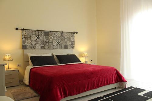 クアルトゥ・サンテーレナにあるcasa carlettaのベッドルーム1室(赤いベッド1台、ランプ2つ、窓付)