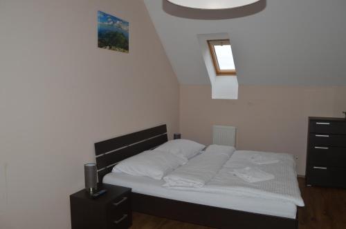 a bedroom with a bed with white sheets and a window at Apartmán Erika in Veľká Lomnica