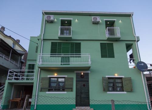 a green building with two balconies and a door at Apartments and spa MIONA in Virpazar