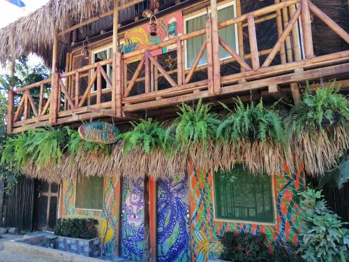 a building with a straw roof and plants on it at La Natura Hostel & Pool in Palomino