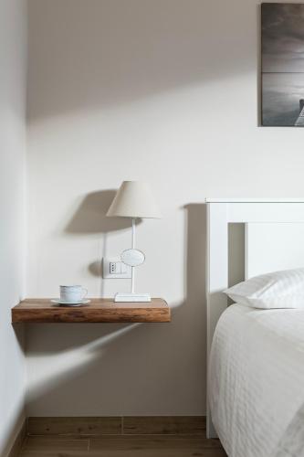 a table with a lamp on a wall next to a bed at Mansarda I Cipressi in Lenno