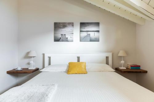 a bedroom with a white bed with a yellow pillow at Mansarda I Cipressi in Lenno