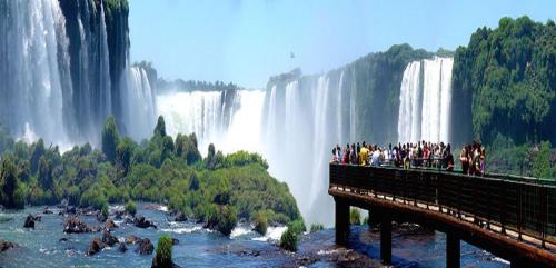 un grupo de personas de pie en un puente frente a una cascada en Departamentos El Chileno en Puerto Iguazú