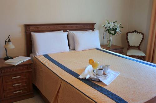 Una cama con una bandeja con una taza y un juguete. en Famissi Hotel en Kalambaka