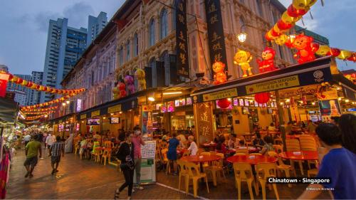 a group of people sitting at tables in a city street at hipstercity hostel in Singapore