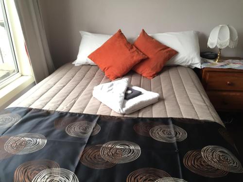 a bed with orange and white pillows on it at Oatlands Retreat in Oatlands