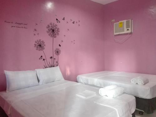 two beds in a room with pink walls at Casa Mirasol in Siquijor