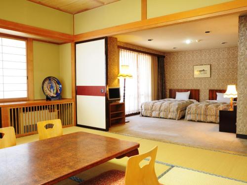 a hotel room with a dining table and a bed at Hotel Grace Hakuba in Hakuba