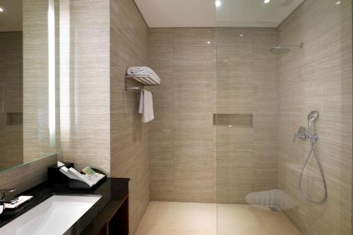 a bathroom with a shower and a sink and a tub at Swiss-Belhotel Airport Jakarta in Tangerang