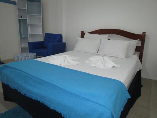 a bed with a blue blanket and a blue chair at La Suite Praia Hotel in Caucaia