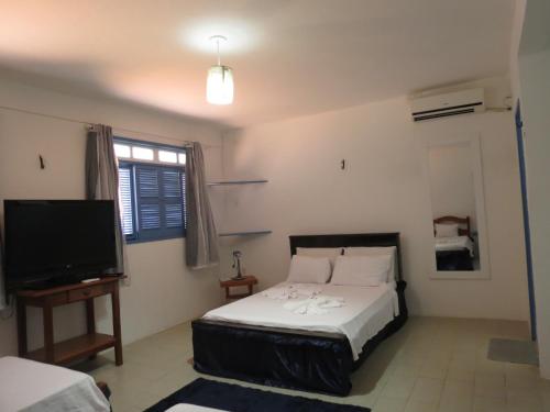 a bedroom with a bed and a flat screen tv at La Suite Praia Hotel in Caucaia