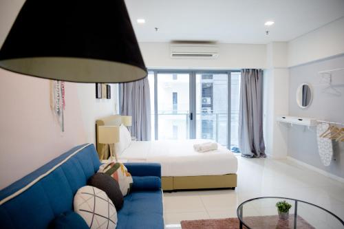 a hotel room with a bed and a blue couch at Summer Suites by Plush in Kuala Lumpur