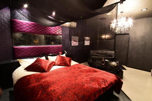 1 dormitorio con cama roja y lámpara de araña en Restay Koakuma (Adult Only), en Utsunomiya