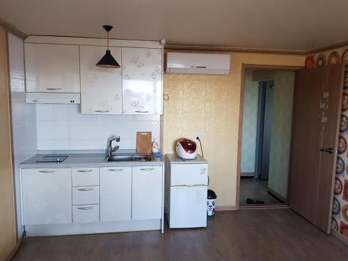 a kitchen with white cabinets and a sink at Purmir Pension in Seogwipo