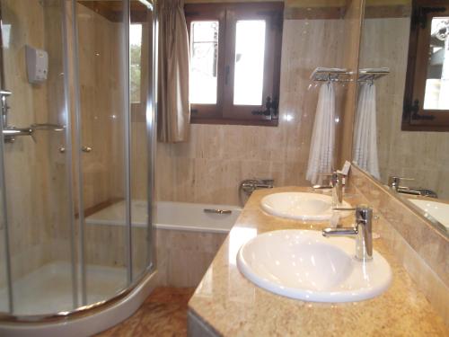 a bathroom with two sinks and a shower at Hotel Termal Abadia de Los Templarios in La Alberca