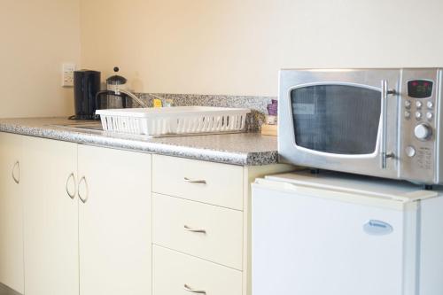 a kitchen with a microwave on top of a counter at Haast River Motels & Holiday Park in Haast