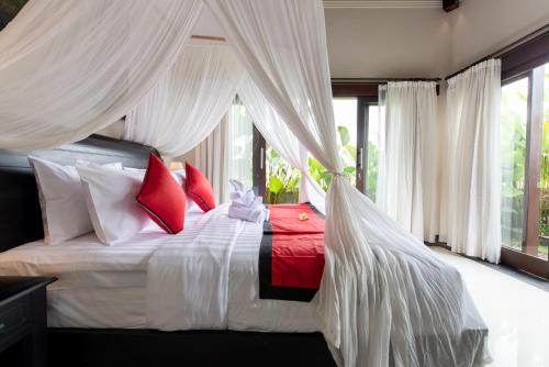 a bedroom with a bed with red and white pillows at Villa Cendrawasih Ubud in Tegalalang
