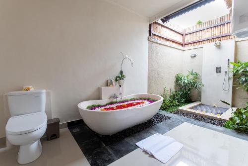 a bathroom with a white tub with flowers in it at Villa Cendrawasih Ubud in Tegalalang