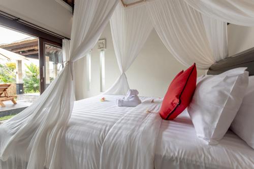 a bedroom with a white bed with red pillows at Villa Cendrawasih Ubud in Tegalalang
