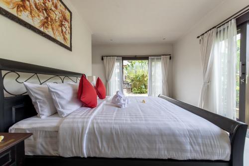 a bedroom with a large white bed with red pillows at Villa Cendrawasih Ubud in Tegalalang