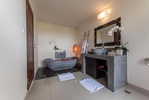 a bathroom with two sinks and a tub and a mirror at Villa Cendrawasih Ubud in Tegalalang
