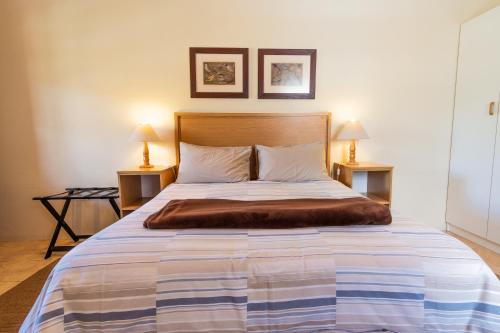 a bedroom with a large bed with two lamps at Treetops Guesthouse in Port Elizabeth