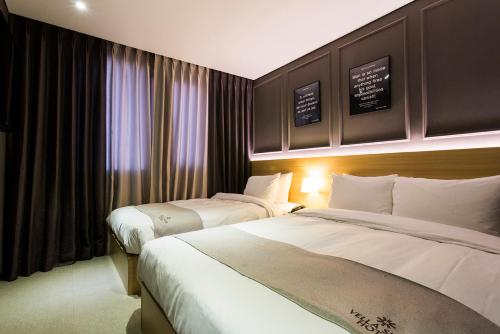 a hotel room with two beds and a window at Vella Suite Hotel in Suwon
