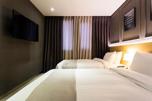 a hotel room with two beds and a flat screen tv at Vella Suite Hotel in Suwon