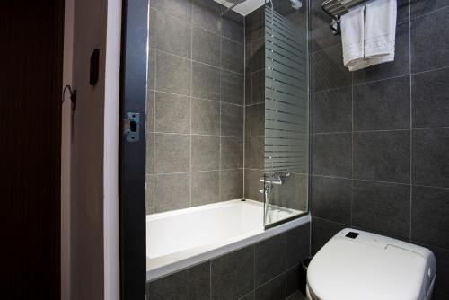 a bathroom with a bath tub and a toilet at Vella Suite Hotel in Suwon