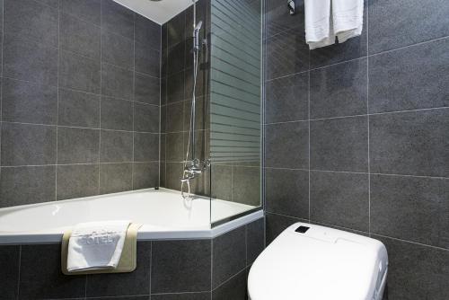 a bathroom with a shower and a toilet and a tub at Vella Suite Hotel in Suwon