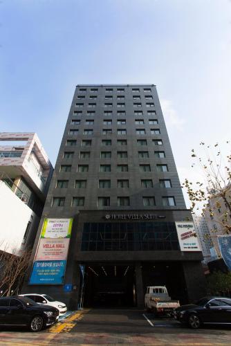 a tall building with a parking lot in front of it at Vella Suite Hotel in Suwon