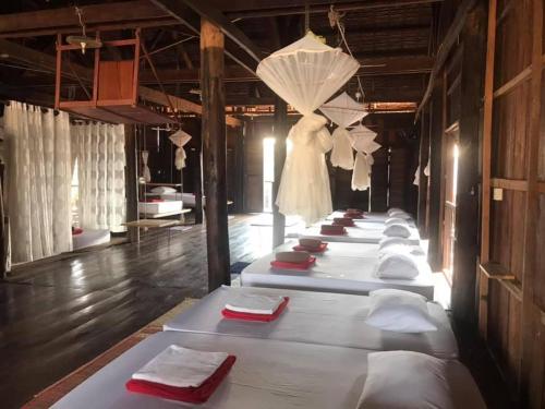 a row of white beds in a room with umbrellas at ST 63 Home Stay & Tour Kampong Khleang in Kâmpóng Khleăng
