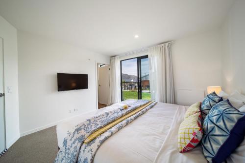 a bedroom with a bed with a tv on the wall at MyHolidays, Shotover, Delux Ensuite rooms in Queenstown