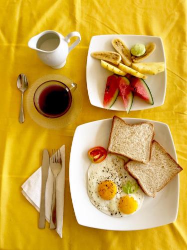 two plates of food with eggs and bread and a cup of coffee at Coppenrath Hostel in Tangalle