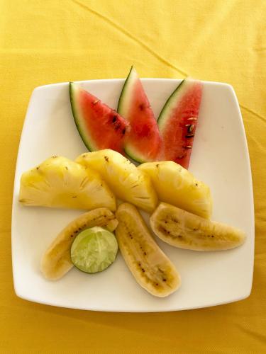 a plate with slices of watermelon and fruit on it at Coppenrath Hostel in Tangalle
