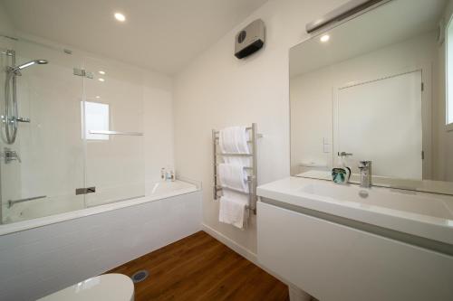 a white bathroom with a tub and a sink at MyHolidays, Shotover, Delux Ensuite rooms in Queenstown