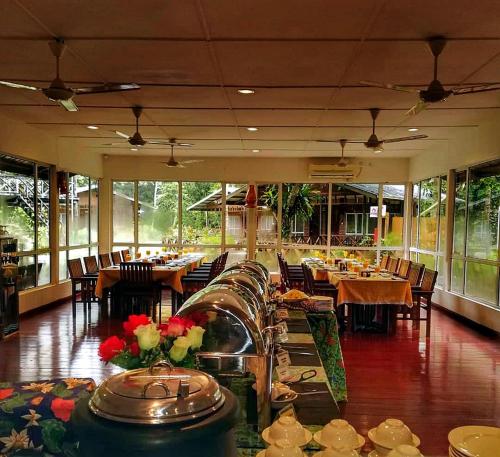 a dining room with tables and chairs and windows at Borneo Nature Lodge in Sukau