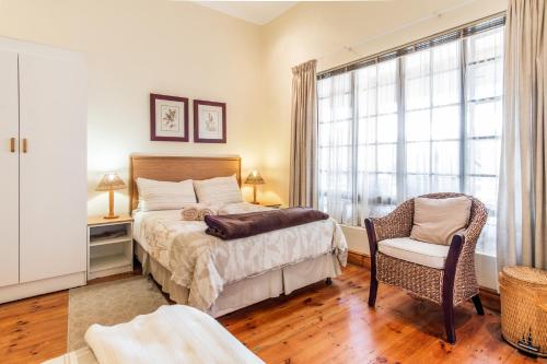 a bedroom with a bed and a chair and a window at Treetops Guesthouse in Port Elizabeth