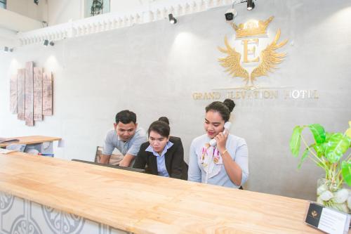 a group of people standing behind a counter at Grand Elevation Hotel in Phnom Penh