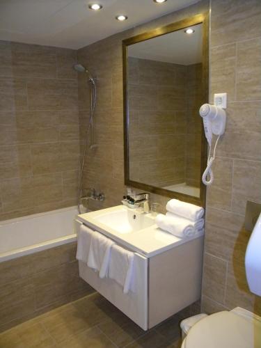 a bathroom with a sink and a mirror and a tub at Bükkös Hotel & Spa in Szentendre