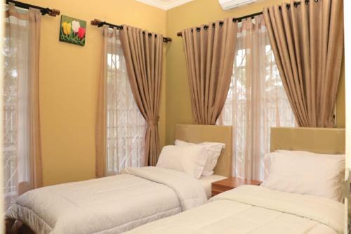 2 Betten in einem Zimmer mit Vorhängen in der Unterkunft Diyar Villas Puncak M3/47 in Puncak