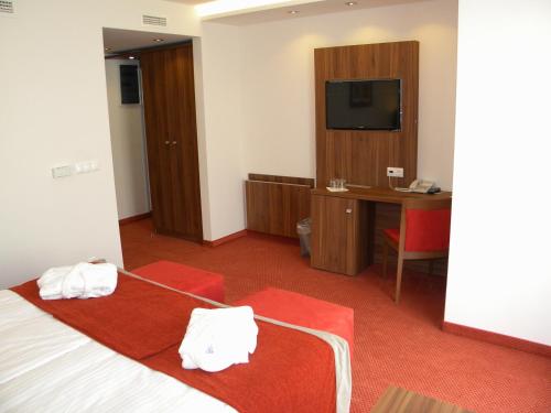 a hotel room with a bed and a desk and a television at Bükkös Hotel & Spa in Szentendre